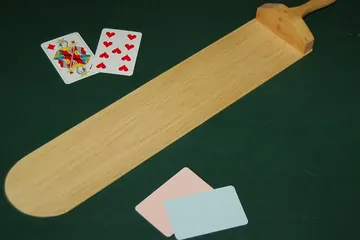 أوراق لعب ومجداف الموزع على طاولة باكارات خضراء